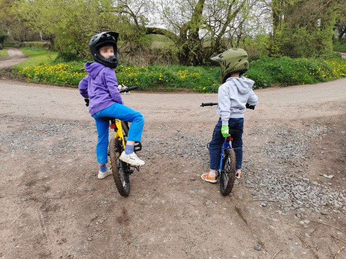 2 boys waiting at a junction of a country lane on their mountain bikes