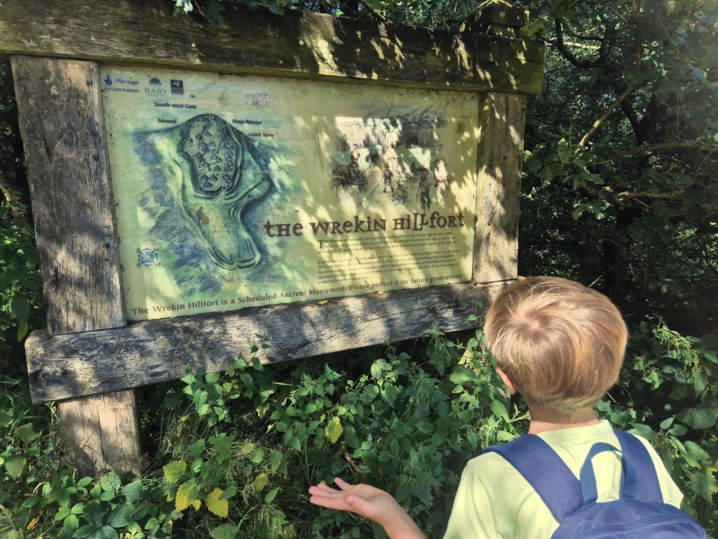 A boy looks at a sign with the words "the wreking hillfort"