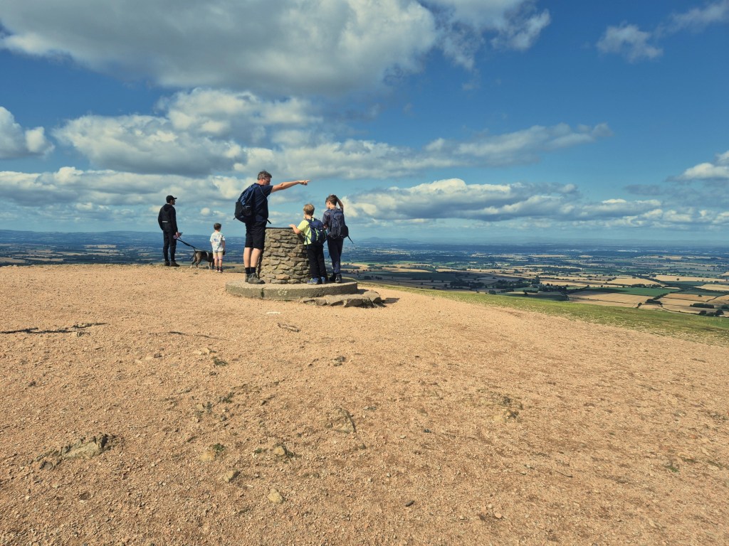 2 boys stand at a toposcope and a man points