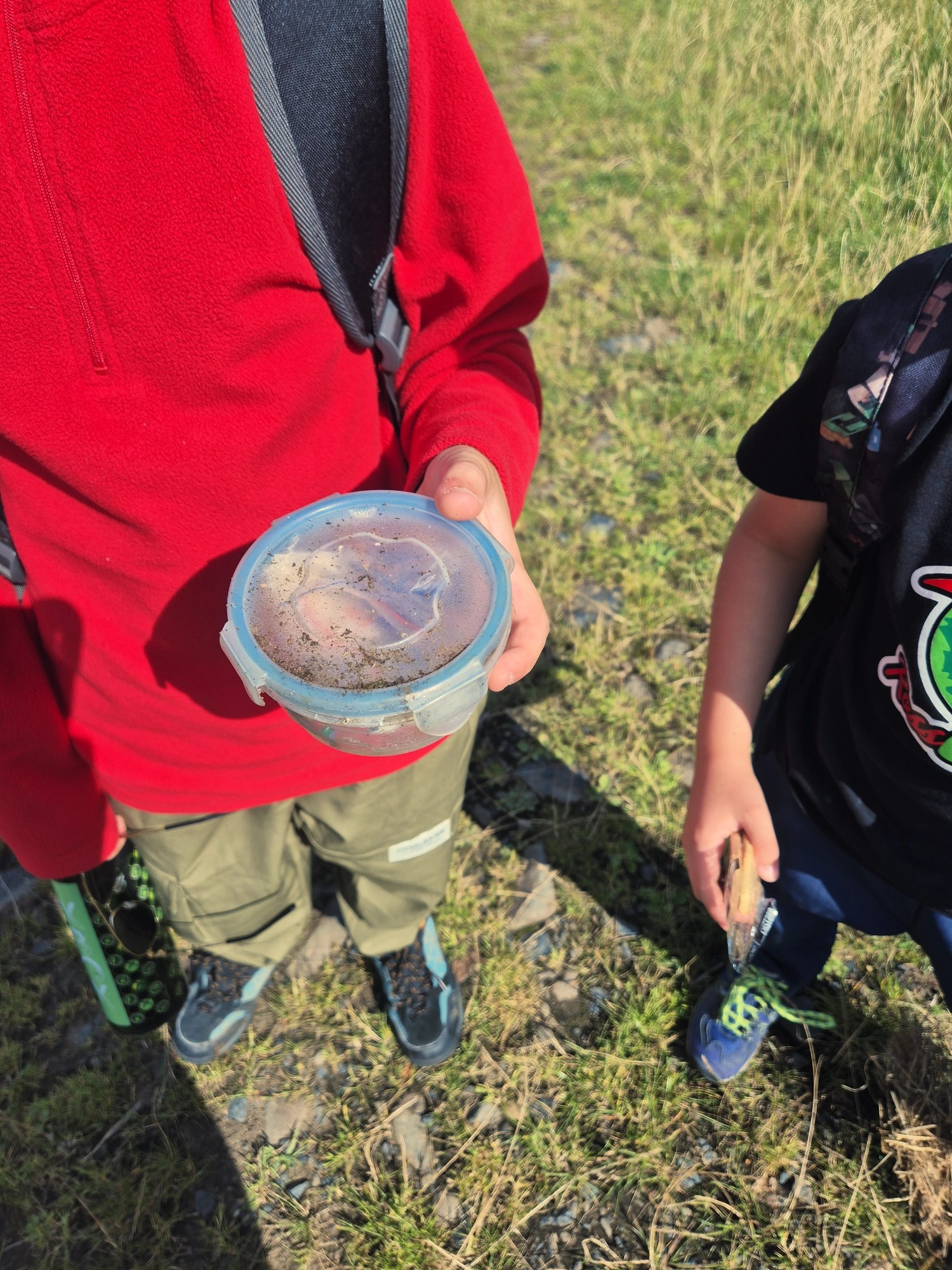 2 boys holding a plastic tub with a geocache
