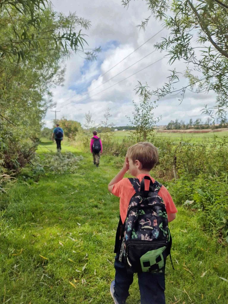 2 boys with backpacks and their dad walk along the Eye Water