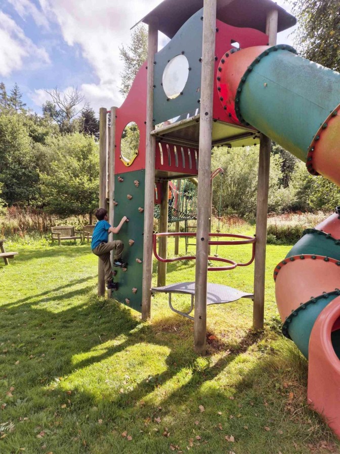 Child climbing up a climbing wall in a park