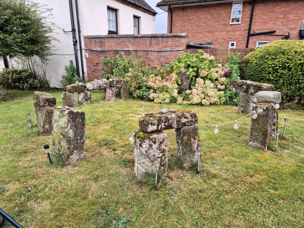 A mini version of stone henge on a grass very with fiary lights