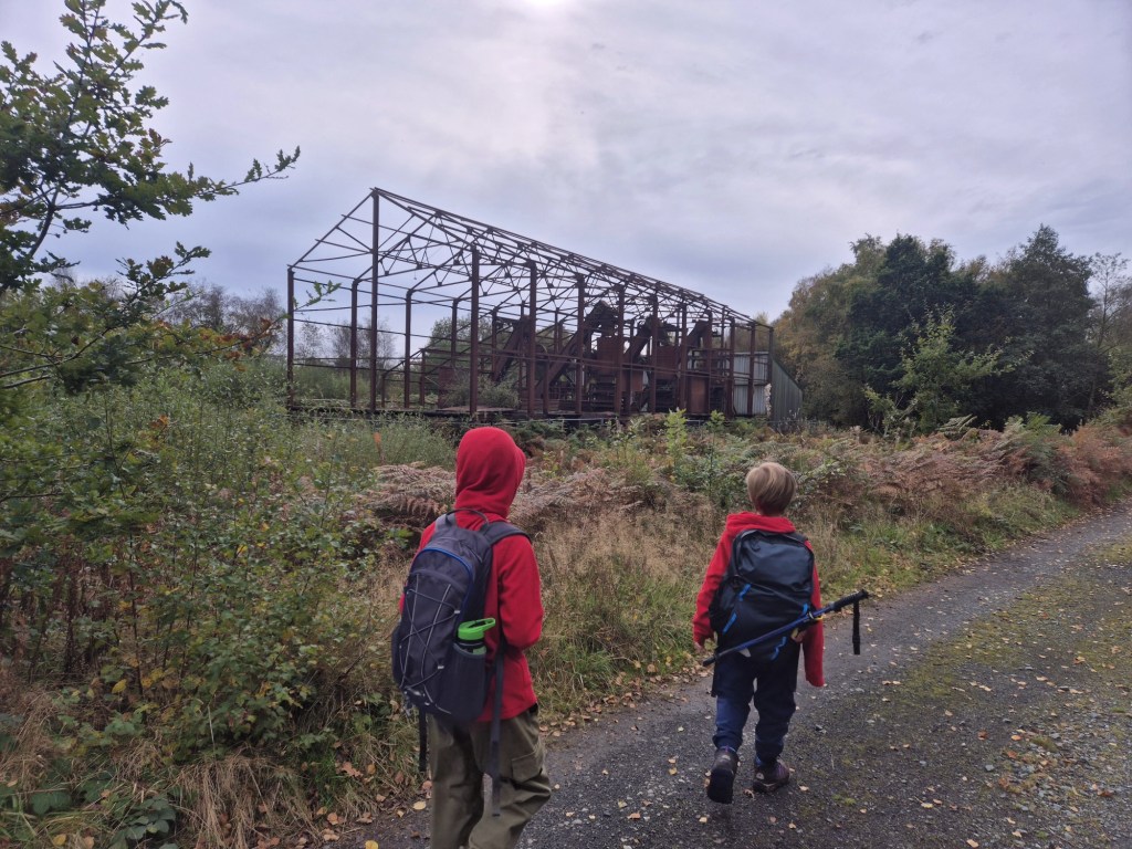 2 boys look toward the skeleton of an old engine shed