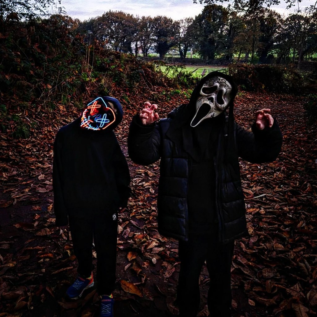 2 boys dressed in black with halloween maskes go for a halloween walk