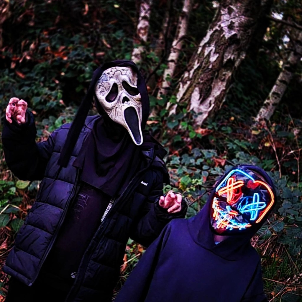 2 boys dressed in black with halloween maskes go for a halloween walk