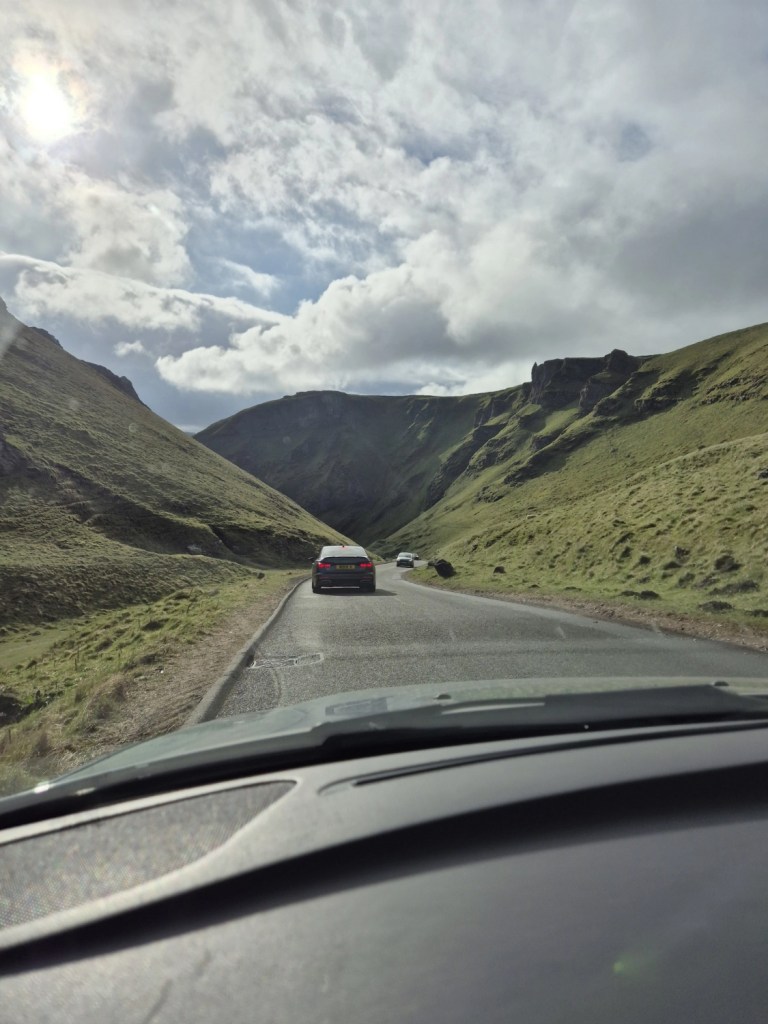 Views from a vehicle looking down a narrow road surrounded by two very steep hillsides