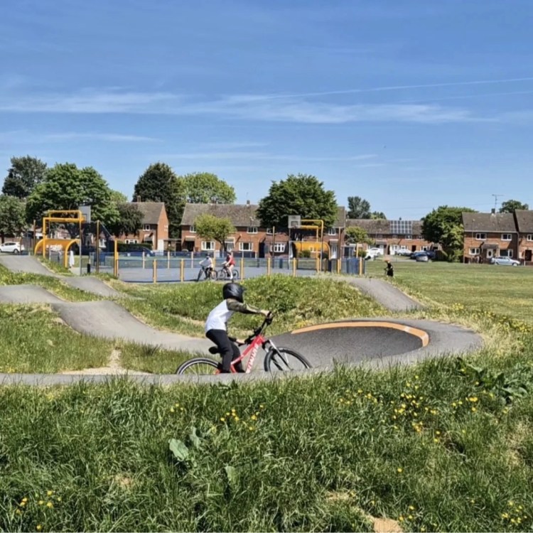 young boy cycling across a berm on a pump track