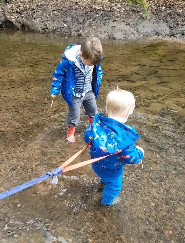 2 small boys paddling in a shallow pool stream river at a reservoir