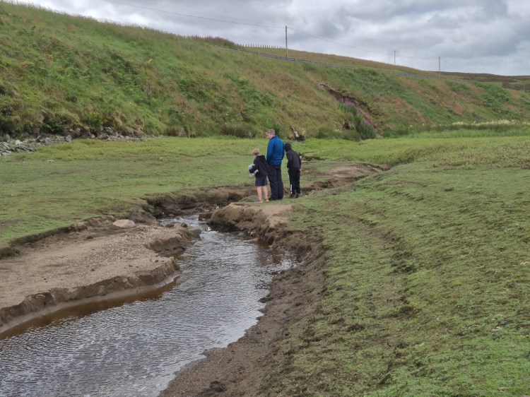 People exploring exposed ground where the reservoir water has receded
