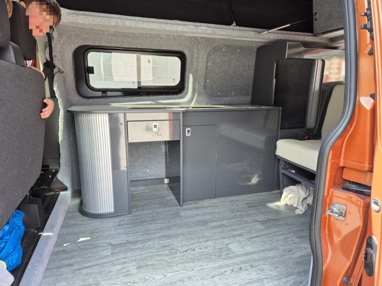 Campervan interior with new grey kitchen units, sink, and cupboards fitted.
