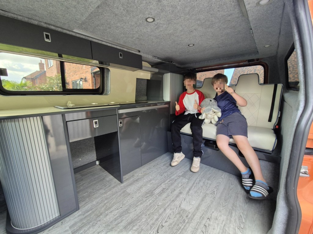 Two children sitting inside the campervan on the new bench seats.