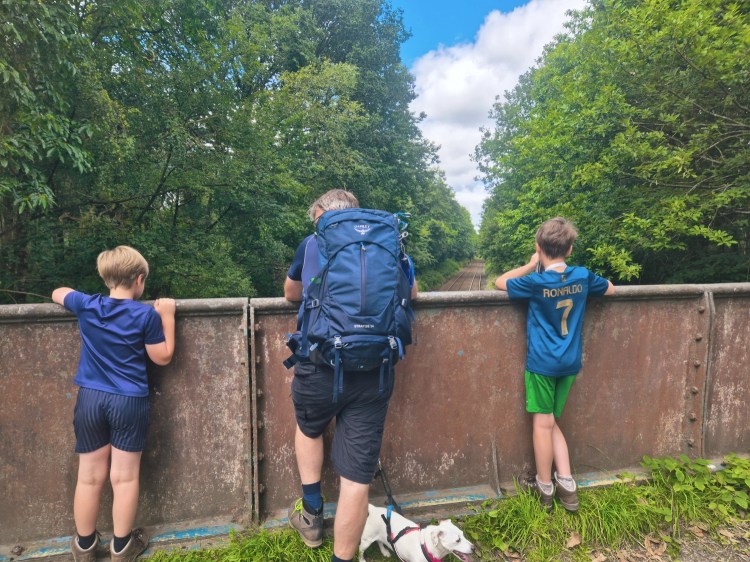 Children peering over a stone railway bridge, hoping to spot a passing train