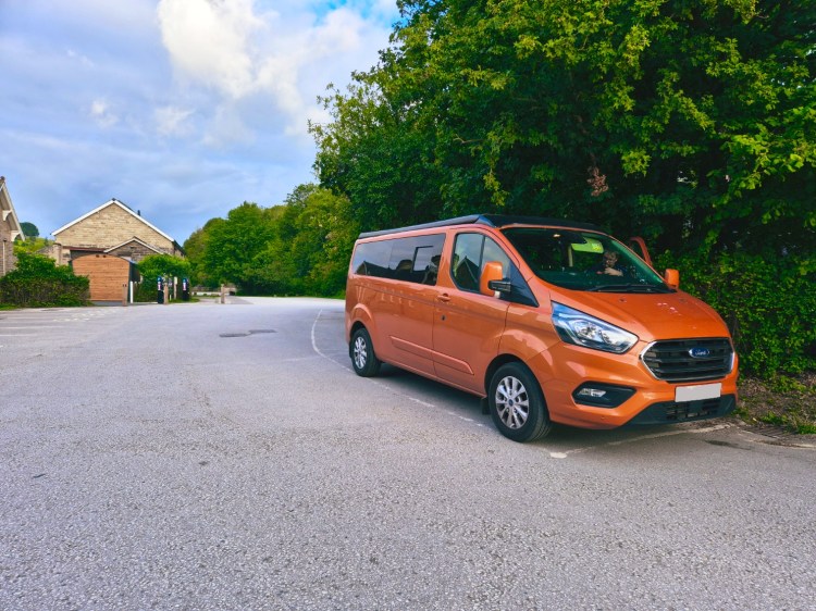 An orange van sits in a desolate car park in the Peak District