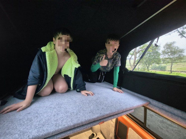 Two boys give the thumbs up in a campervan pop tup in the Peak District